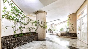 A lobby with marble flooring, a central column, and greenery on the walls. - Home Holidays 204 (CN)