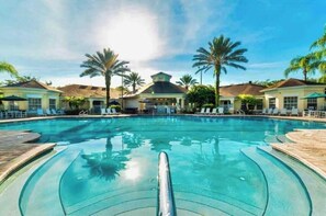 Une piscine avec des chaises longues et des palmiers.