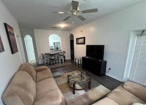 A living room with a ceiling fan, a TV, and a sofa. - Beautiful 2-bedroom condo in a serene gated community with refreshing AC (Kissimmee)