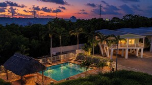 A pool area with a thatched-roof structure, a covered seating area, and a view of the ocean at sunset. - *NEW!*Life is a Marathon~VIEWS!~Pool~Dock~HotTub! (Marathon)
