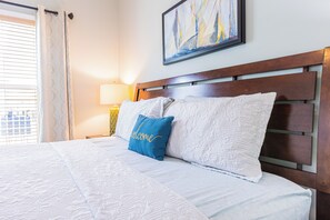 Ein Hotelzimmer mit Bett, Kopfteil, Nachttisch, Lampe und einem Bild an der Wand.