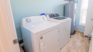 A laundry room with a front-loading washer and dryer, a water heater, and a window with blinds. - *NEW!*Life is a Marathon~VIEWS!~Pool~Dock~HotTub! (Marathon)