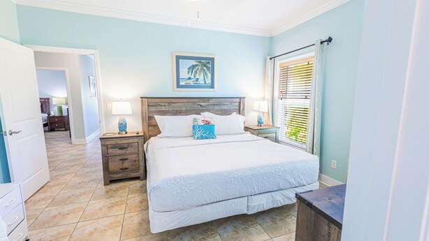 A bedroom with a bed, bedside tables, a nightstand, a framed picture on the wall, and a window with blinds. - *NEW!*Life is a Marathon~VIEWS!~Pool~Dock~HotTub! (Marathon)