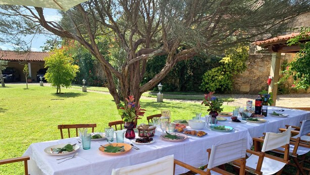 An outdoor dining area with tables set for a meal, surrounded by greenery and a stone wall. - MyStay - Casa Guito Rural House (Cepões)