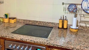 A kitchen with a granite countertop, a built-in stove, and a dish rack with plates. - MyStay - Casa Guito Rural House (Cepões)