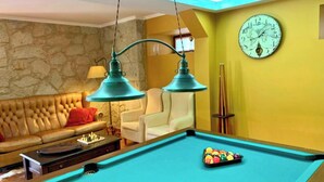 A billiards table with balls, a clock, and two lamps in a room with a stone wall and a yellow wall. - MyStay - Casa Guito Rural House (Cepões)