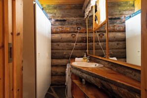 Ein Badezimmer in einer Blockhütte mit einem Holzbadezimmer-Schrank, einem Waschbecken und einem Spiegel.