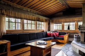Ein Holzblockhaus-Interieur mit einer Couch, einem Tisch und einem Kamin.