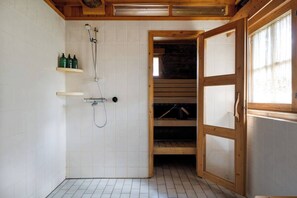 Ein Badezimmer mit Dusche, Holzregalen und einem Fenster.