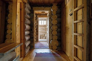 Ein rustikales Blockhaus mit einer Holztür in der Mitte, Holzwänden und Holzboden.