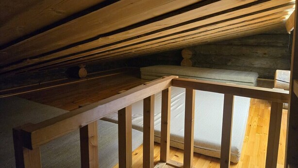 Et soveværelse på loftet med træloft, en seng og et lille vindue.