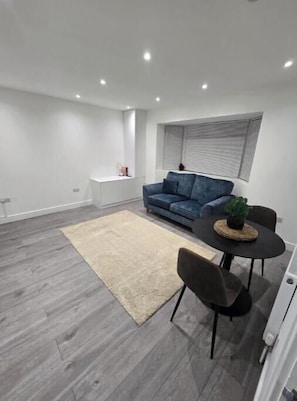 Ein modernes Wohnzimmer mit einem blauen Sofa, einem runden Tisch und einem beigen Teppich.