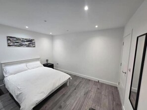 Ein Schlafzimmer mit Bett, Nachttisch, Wandkunst und einer Tür.