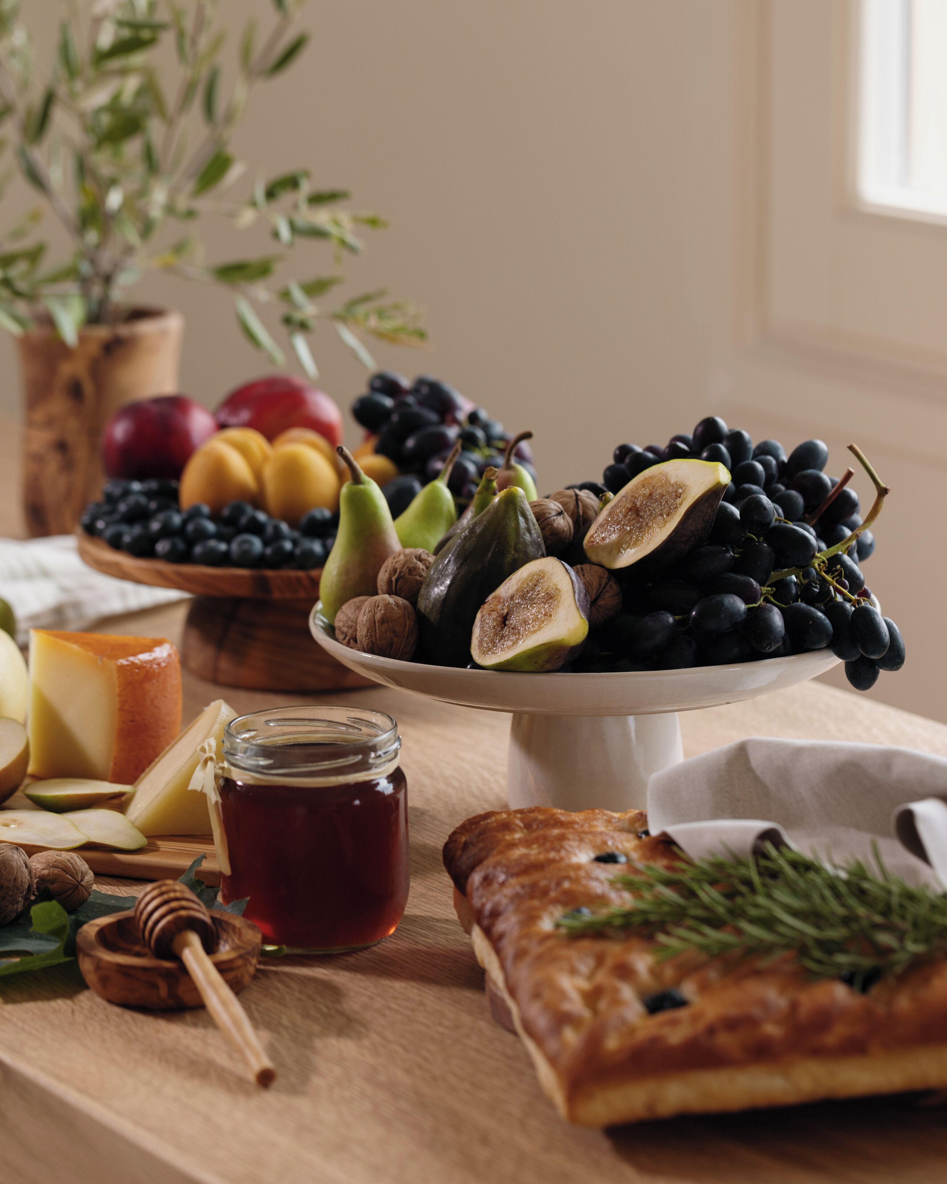 Une table garnie d’une variété de fruits, d’un pot de miel et d’une pâtisserie.