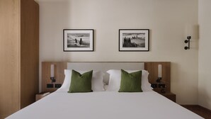 A hotel room with a large bed, two green pillows, a wooden headboard, and two framed pictures on the wall. - The Podere Wine Resort Chianti (Barberino Tavarnelle)