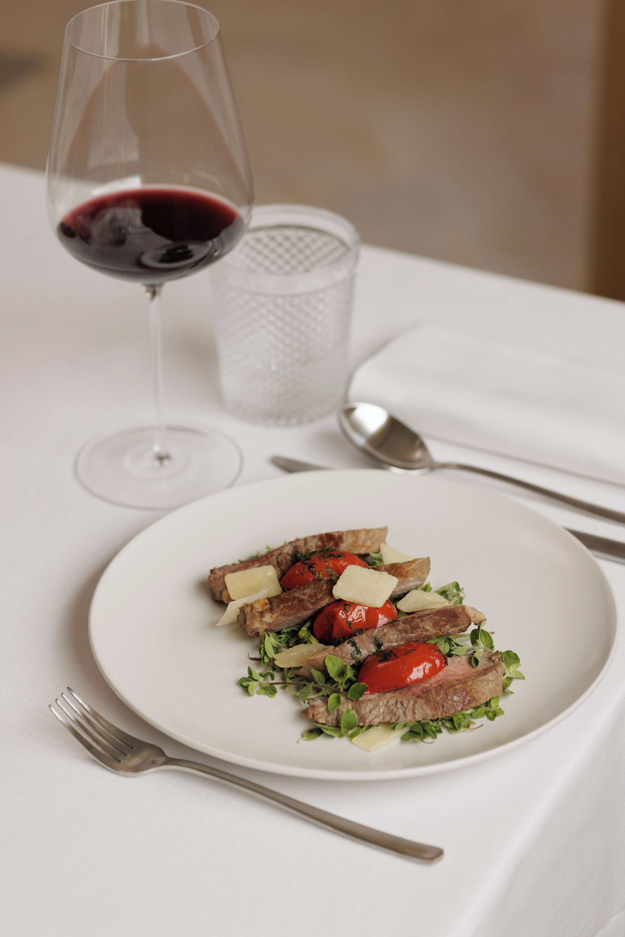 A plate of food with a glass of red wine and a glass of water on a table.