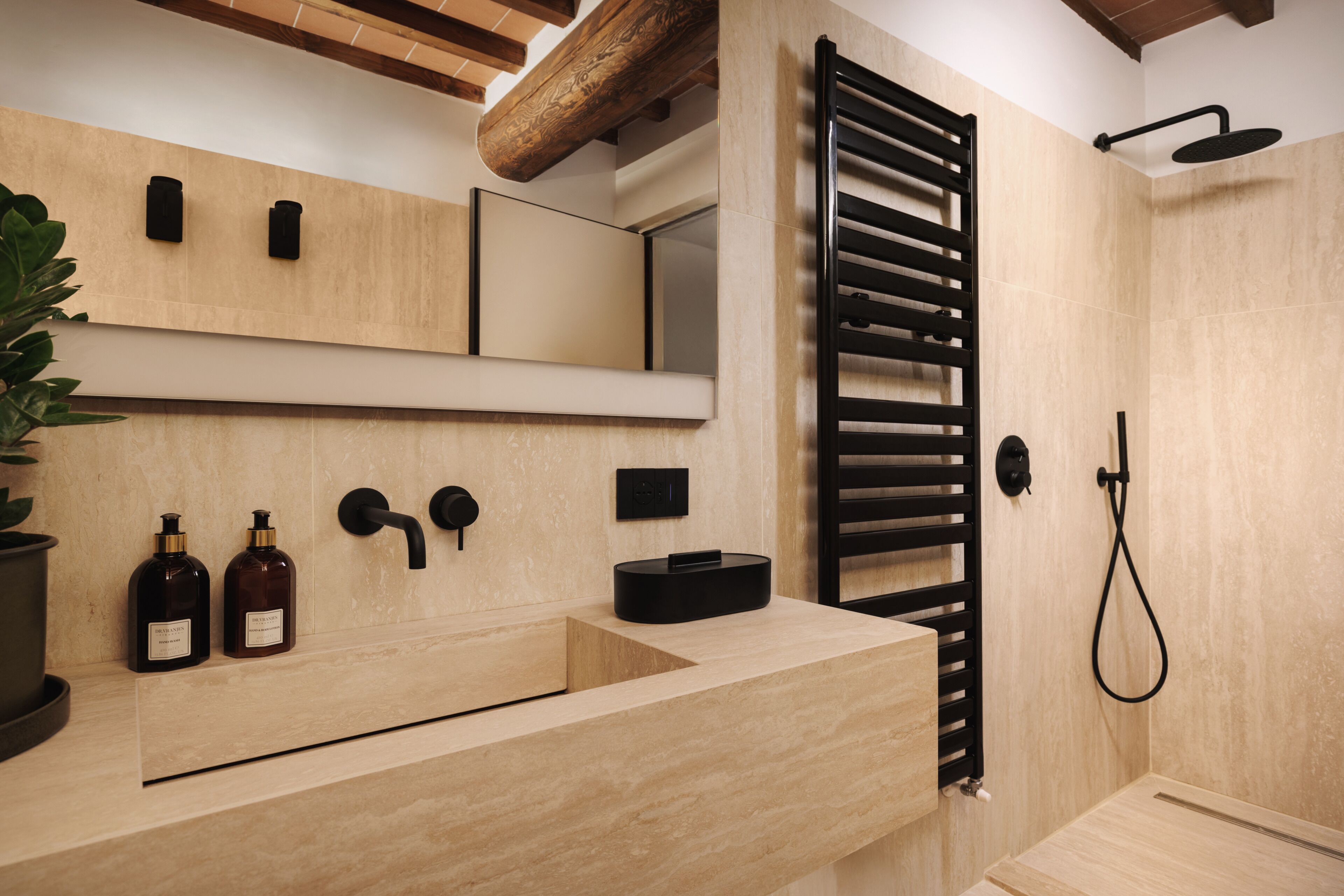 A modern bathroom with a wooden vanity, a towel rack, and a shower area.