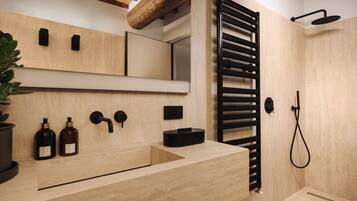A modern bathroom with a wooden vanity, a towel rack, and a shower area.