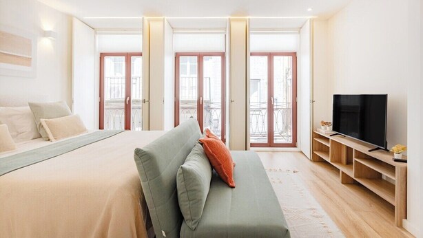 A bedroom with a bed, a sofa, a TV, and a balcony with a railing. - Studio Central 111 Collection (Porto)