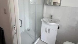 Un bagno con cabina doccia in vetro, un lavandino bianco e un water.