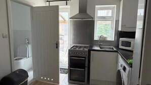 Una cucina compatta con piano cottura a gas, forno, microonde e lavatrice.
