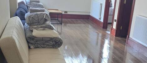 Una habitación amplia con un sofá grande, un radiador y una puerta que da a otra habitación.