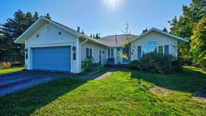A single-story house with a garage, a front porch, and a well-maintained lawn. - The Cottage at New Chelsea (New Chelsea)