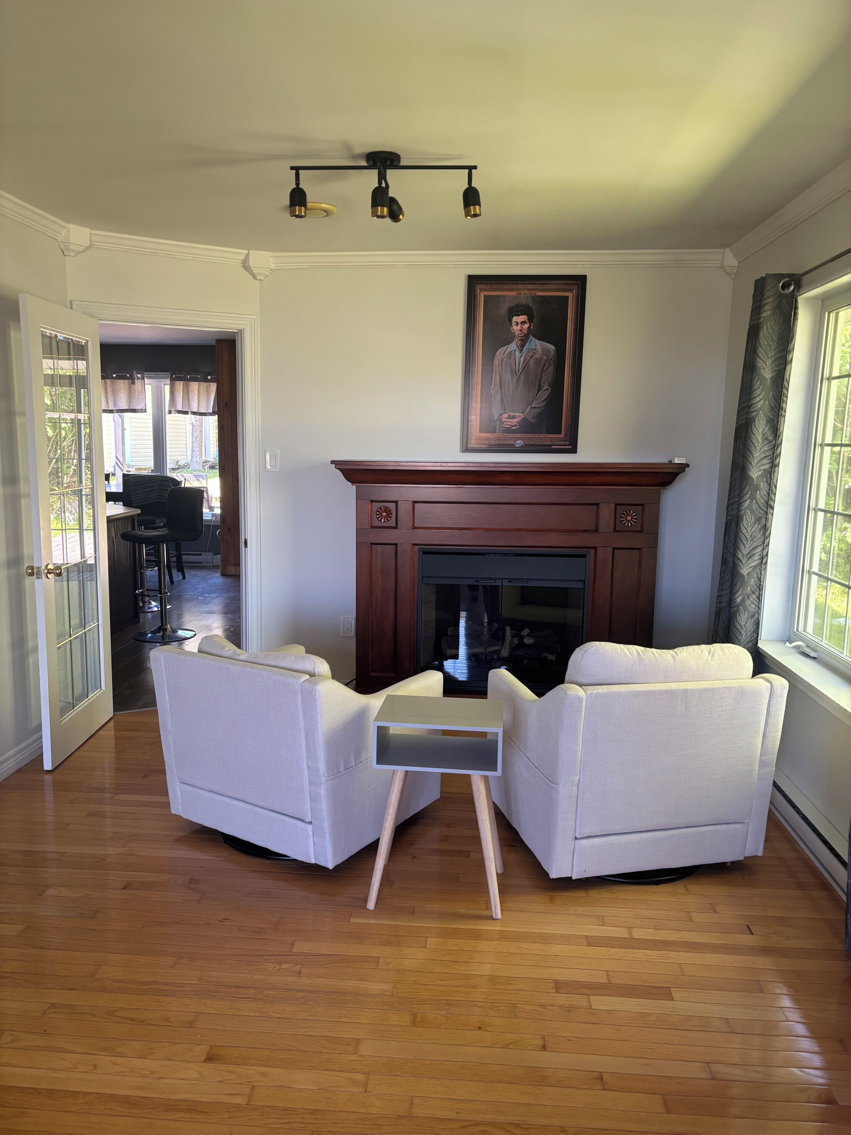 A living room with a fireplace, two armchairs, a small table, and a ceiling fan.