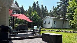 A wooden deck with outdoor furniture, a hot tub, and a stone wall. - The Cottage at New Chelsea (New Chelsea)
