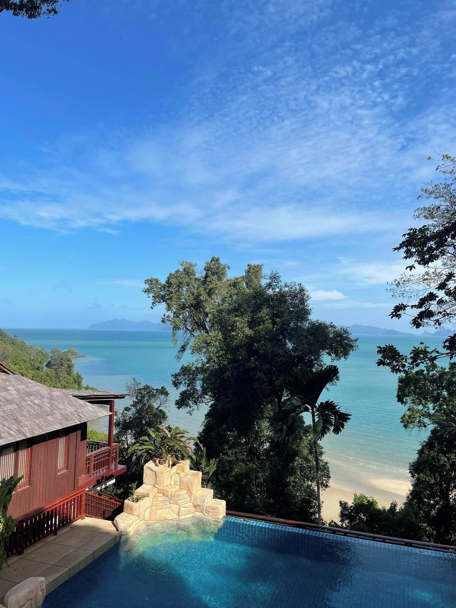 A pool with a view of the ocean and a beach.
