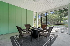 Un patio cubierto con mesa y sillas, un hogar para fogata y vistas al exterior.