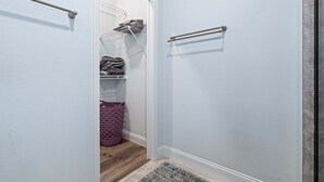 Un pasillo con una puerta que da a un área de lavandería, un perchero de metal y piso de madera.