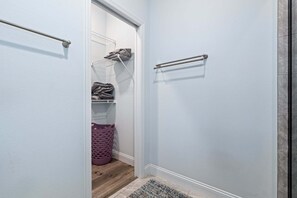 Un couloir avec une porte donnant sur une buanderie, un porte-serviettes en métal et un plancher en bois.