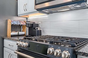 Una cocina con estufa a gas, horno y cafetera.