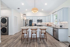 Une cuisine moderne dotée d’un îlot central, de tabourets de bar, d’appareils électroménagers en acier inoxydable et de meubles de couleur bleu clair.