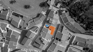 Vista aérea de uma área residencial com uma praça central, rodeada por casas com arquitetura uniforme, um pequeno edifício azul e uma área laranja bem definida.