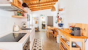 Cozinha moderna com vigas de madeira, fogão, pia e área de jantar com mesa e cadeiras.