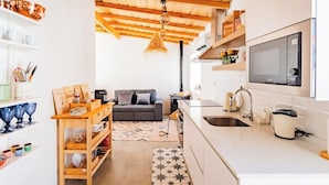Uma cozinha compacta com teto de madeira, um sofá e um espaço de refeições com mesa e cadeiras.