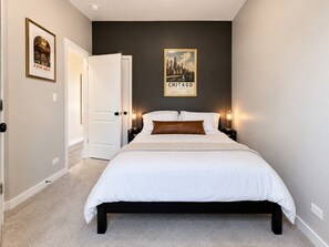 A bedroom with a bed, a door, and a wall with a poster.