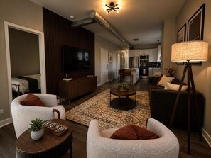 Ein modernes Wohnzimmer mit einer Couch, Sesseln, einem Couchtisch und einem Fernseher.