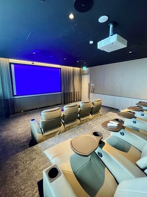 Ein Kino mit Reihen von Sitzen, einer großen Leinwand und einem Projektor.