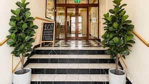 Un imponente acceso con una araña, un cartel que ofrece un descuento del 10% y plantas en macetas a ambos lados de la escalera.