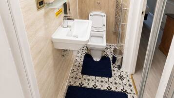 A bathroom with a sink, toilet, and shower area.