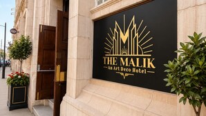 Fachada de un edificio con un letrero que dice 'The Malik Art Deco Hotel'.