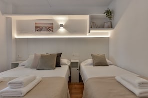 A hotel room with two beds, each with a white bedspread and multiple pillows. There is a small shelf with decorative items and a framed picture above the beds. - Paraiso Mar Apartments in Calpe VICTORIA (Calpe / Calp)