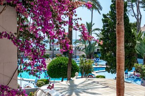 A pool area with lounge chairs, palm trees, and a view of the sea. - Paraiso Mar Apartments in Calpe VICTORIA (Calpe / Calp)