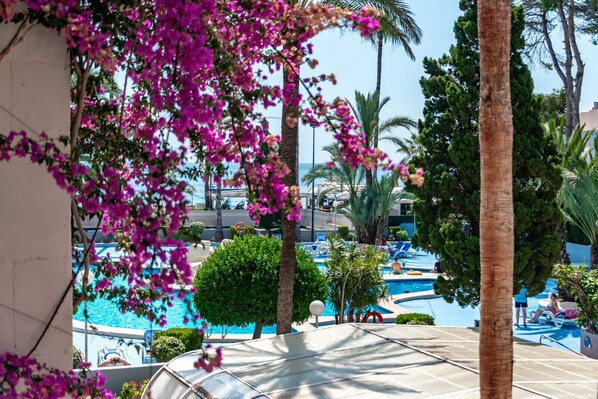 A pool area with lounge chairs, palm trees, and a view of the sea. - Paraiso Mar Apartments in Calpe VICTORIA (Calpe / Calp)