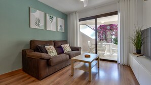A living room with a brown sofa, a small wooden table, and a TV on a white cabinet. - Paraiso Mar Apartments in Calpe VICTORIA (Calpe / Calp)