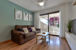 A living room with a brown sofa, a small wooden table, and a TV on a white cabinet. - Paraiso Mar Apartments in Calpe VICTORIA (Calpe / Calp)