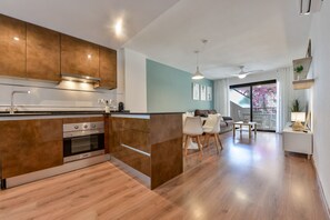 A modern kitchen with wooden cabinets, a built-in oven, and a dining area with a table and chairs. - Paraiso Mar Apartments in Calpe VICTORIA (Calpe / Calp)